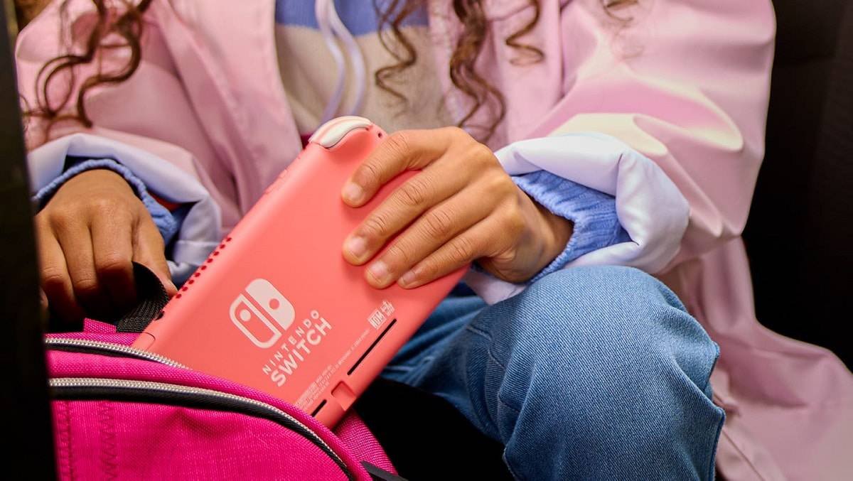 coral Nintendo Switch Lite being placed into a carrying pouch