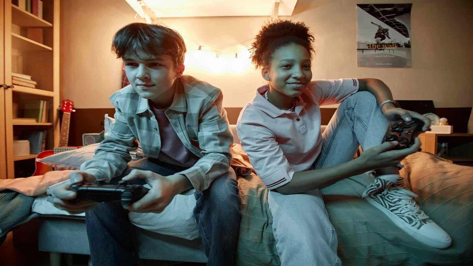 Two teenagers playing video games together at night, smiling and focused on the screen